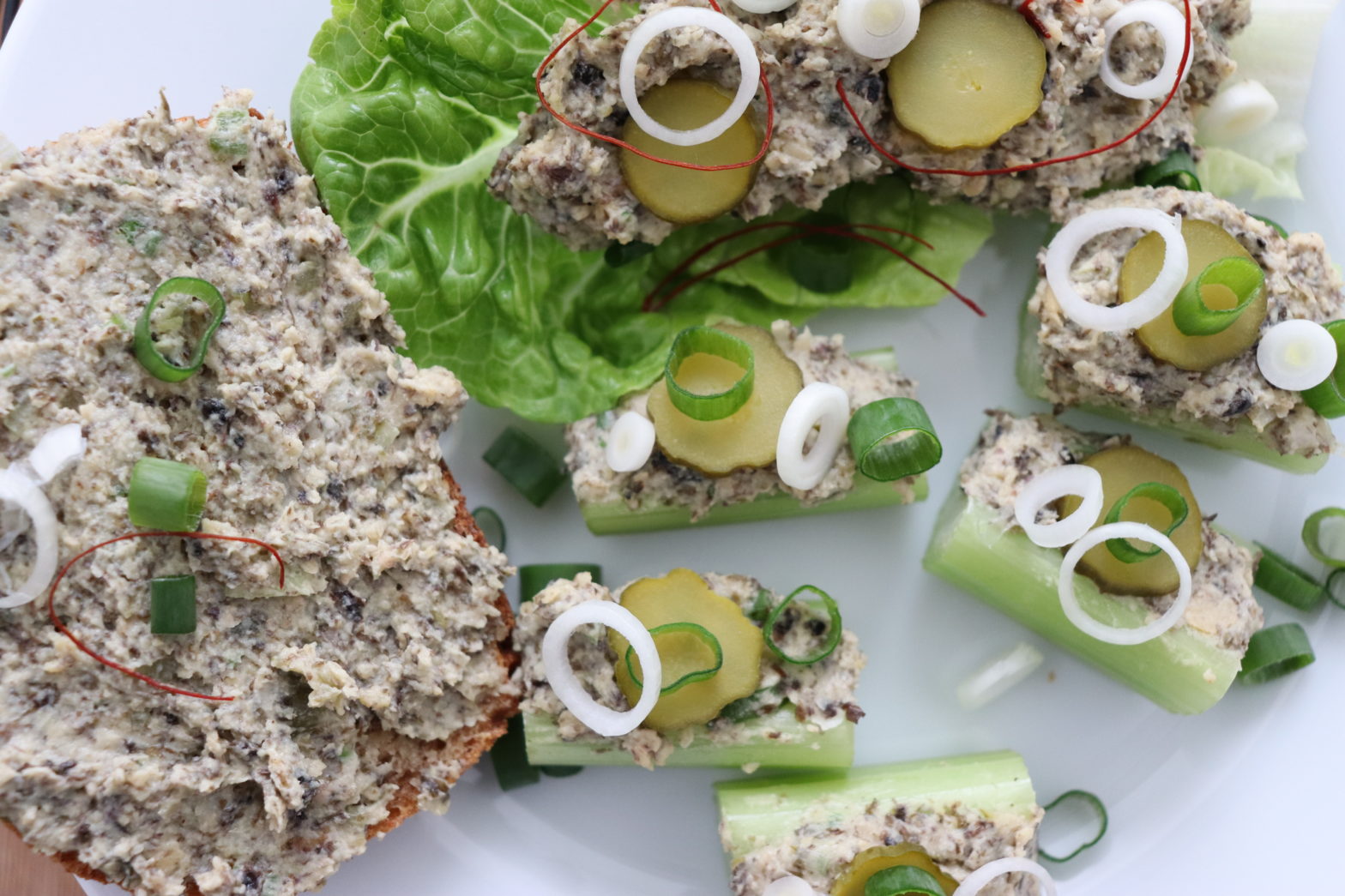 Teller mit einer Schnitte, Salatblatt und Staudensellerie belegt mit veganem Thunfischsalat